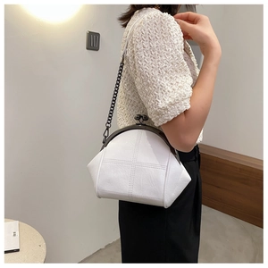 White shell cross-stitch leather bag with black chain strap on model shoulder
