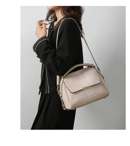 Close-up of cream crocodile pattern handbag showing texture and gold metal detail