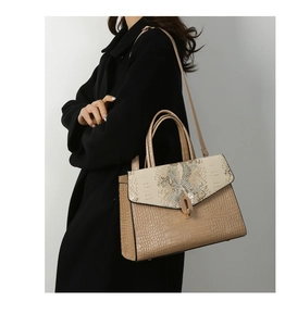 Brown crocodile pattern handbag with snake skin detail on black coat-clad model