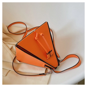 Détail du sac triangulaire orange en cuir avec cordon sur un blazer de couleur beige