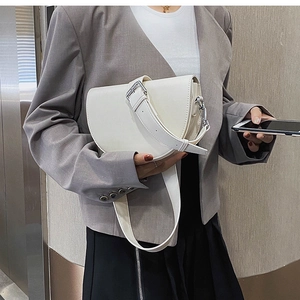 Détail du sac selle blanc avec large bandoulière en cuir et boucle en métal argenté