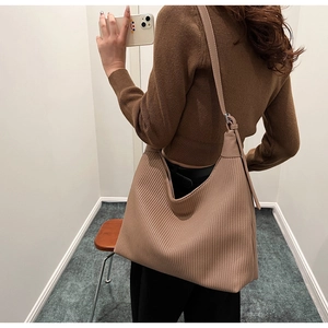 Détail du sac hobo montrant la texture plissée verticale et la couleur beige sur l'épaule