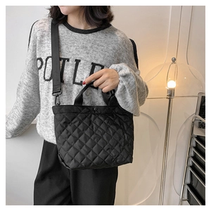 Dettaglio della borsa tote in nylon trapuntato nero con ampia tracolla indossata dal modello