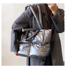 Detailed macro view of the silver metallic quilted texture and puffy down fabric on tote bag