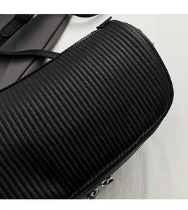 Close-up of black crossbody bag showing textured embossed pattern and silver zipper detail