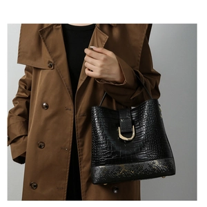 Detail of black crocodile texture handbag with snake skin trim and gold D-ring hardware