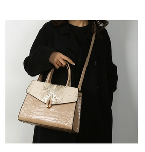 Detail of beige and khaki crocodile embossed handbag with snake pattern flap and gold lock
