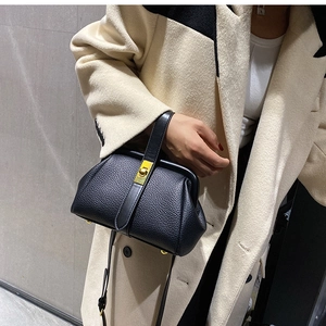 Detail of black lychee grain leather crossbody bag with gold metal twist lock on model