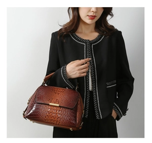 Detail of gradient reddish-brown crocodile pattern leather handbag with gold metal clasp