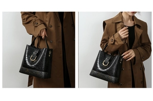 Detail of black crocodile texture bucket bag with gold U-shaped metal buckle and handle