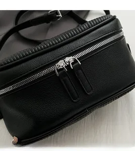 Close-up of black lychee grain leather bag with smooth double silver zippers and pleats