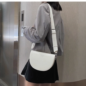 Sacoche selle en cuir blanc avec large bandoulière sur un mannequin en blazer