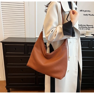 Détail de la texture plissée marron et du cuir du grand sac hobo porté à l'épaule