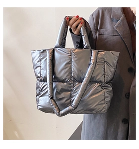 Detail of metallic silver padded tote bag showing quilted down fabric texture and sheen