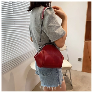 Detail of red leather shell bag showing the vintage metal frame and stylish chain strap