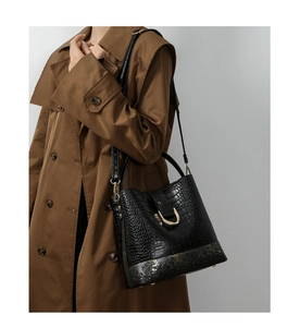 Detail of black crocodile texture bucket bag with gold hardware and d-ring buckle