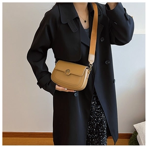 Detail of khaki leather crossbody bag featuring a round metal buckle and wide strap