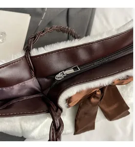Detail of smooth metal zipper on fuzzy white faux fur tote bag with brown leather trim