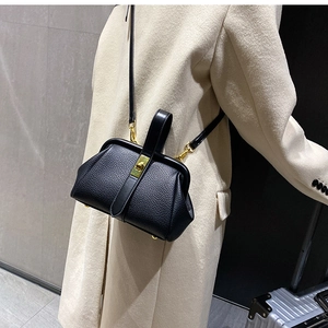Side view of a black lychee-grain leather crossbody bag worn by a model in travel scene