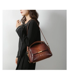 Detail of brown crocodile pattern handbag featuring gold buckle and textured leather finish
