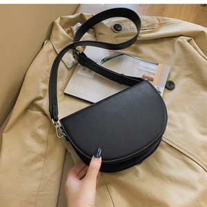 Détails du sac de selle noir en similicuir grainé avec une large bandoulière confortable