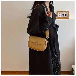 Detail of vintage camel saddle bag featuring a round metal buckle and wide strap