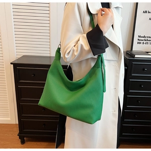 Détail du cabas vert vif avec plis verticaux et bandoulière robuste sur manteau blanc