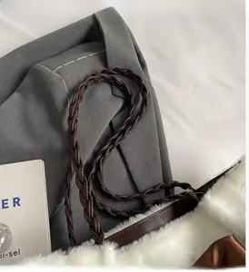 Detail of white plush tote bag showing braided brown leather handle and soft texture