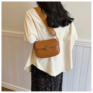Brown vintage leather shoulder bag with classic metal buckle and wide strap on model