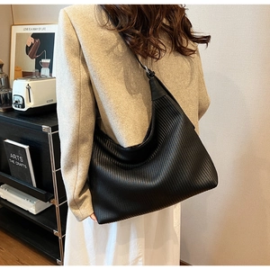 Vue détaillée d'un grand sac hobo noir en cuir rayé porté par un mannequin