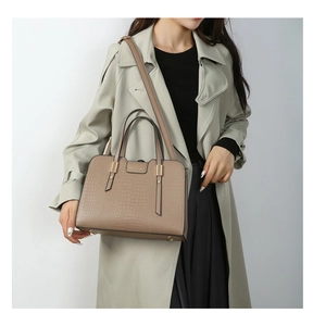 Detail of khaki crocodile embossed handbag with gold hardware and shoulder strap