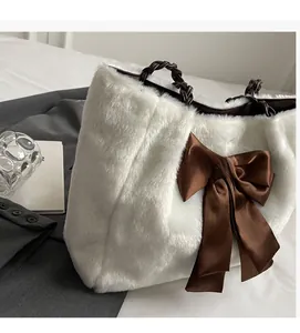 Close-up of white fluffy plush tote bag featuring a large brown satin bow and woven handle