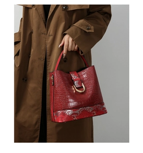 Close-up of red handbag featuring embossed crocodile and snakeskin patterns with gold lock