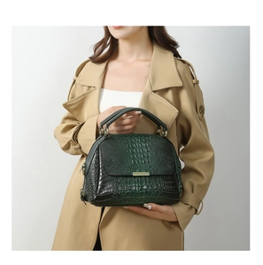 Detail of dark green crocodile pattern leather handbag with gold metal lock hardware