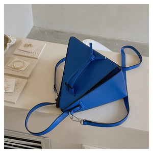 Détail d'un sac bandoulière triangulaire bleu foncé avec sangle nouée et boucles en argent