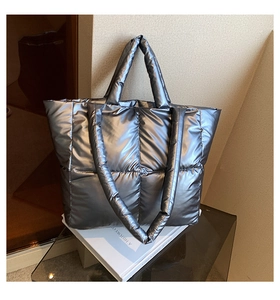 Detail of silver metallic quilted tote bag with high-gloss finish and padded shoulder strap