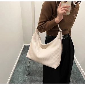 Détail d'un grand sac fourre-tout blanc crème avec plis verticaux porté par un mannequin