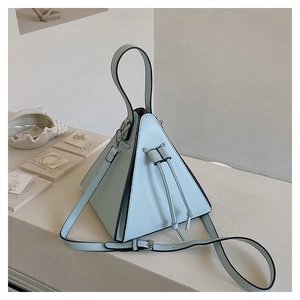 Gros plan d'un sac pyramide bleu clair en cuir avec détails métalliques et bandoulière