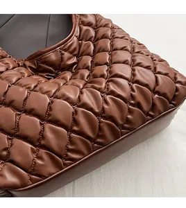 Detailed macro view of brown quilted faux leather texture with precision hand stitching