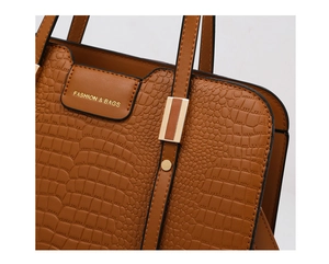 Detail of caramel brown handbag with crocodile embossed leather and golden hardware