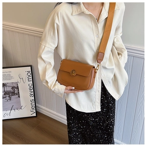 Brown faux leather square crossbody bag featuring a wide orange woven strap on a model