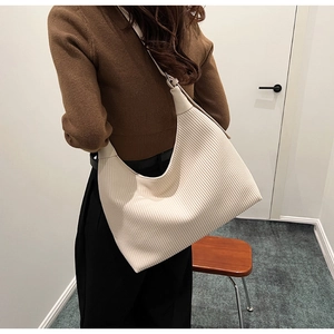 Détail de la texture plissée verticale et de la large bandoulière du sac blanc