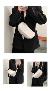 Detail of white pleated texture and dual zipper design on a stylish crossbody bag