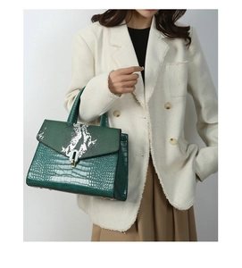 Detail of dark green handbags with crocodile texture and snake print flap for women