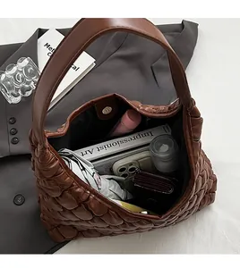 Spacious interior of brown quilted tote bag showing daily essentials and book
