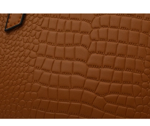 Macro detail of brown crocodile embossed faux leather texture on fashionable handbag