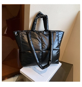 Detail of black quilted puffer tote bag with glossy finish and square stitch pattern