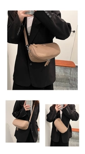 Detail view of khaki cylindrical crossbody bag with vertical pleated texture and silver zipper