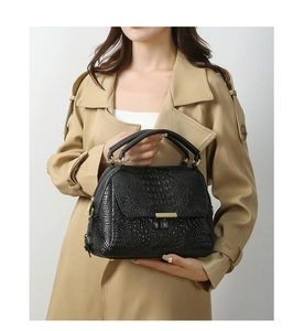 Close-up of black crocodile pattern leather handbag featuring golden metal hardware