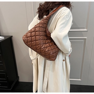 Detail shot of a dark brown quilted hobo bag styled with a cream trench coat